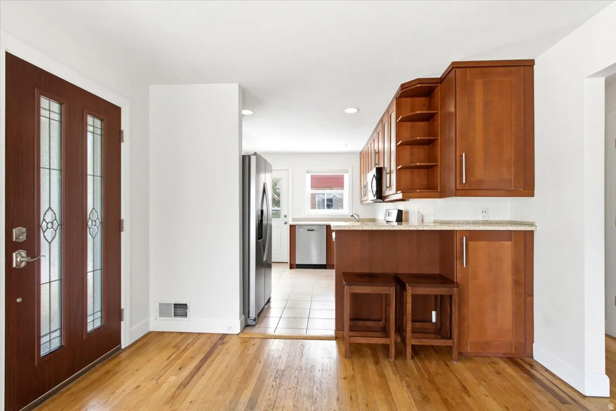 Hardwood flooring extends from the entry, complementing the wood cabinetry and light-toned countertops