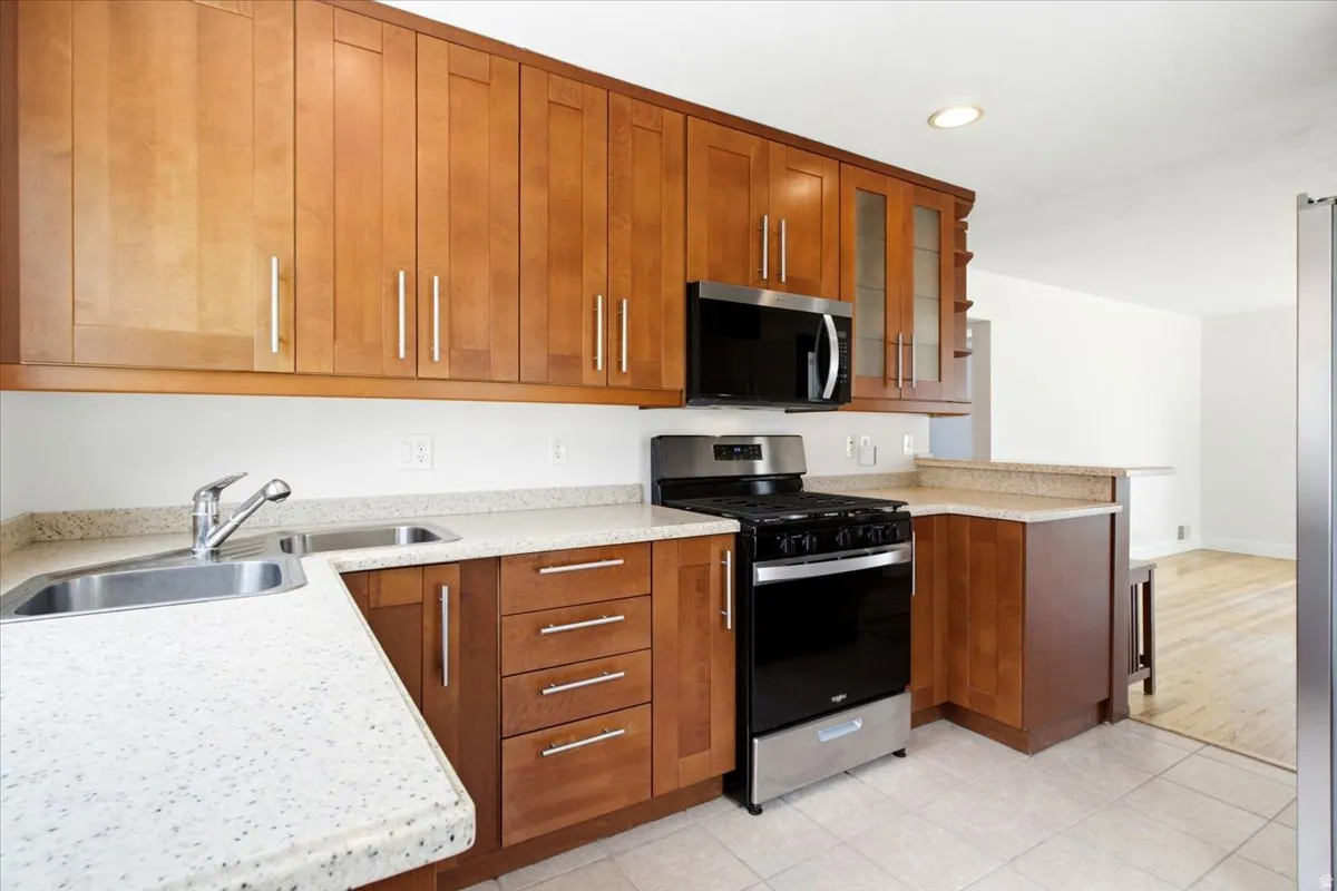 Kitchen featuring wood cabinetry, stainless steel appliances, granite-finish countertops, and a double basin sink