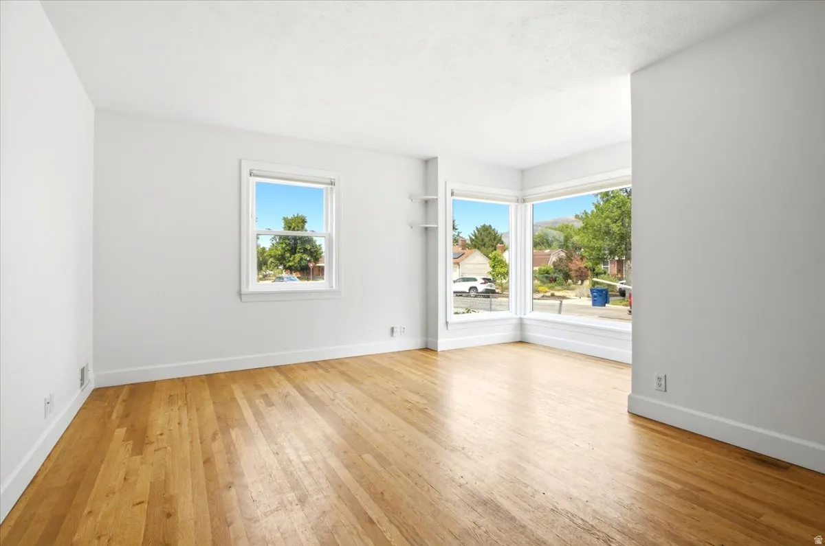 Spacious room featuring wood-finish flooring, white walls, and bright white trim