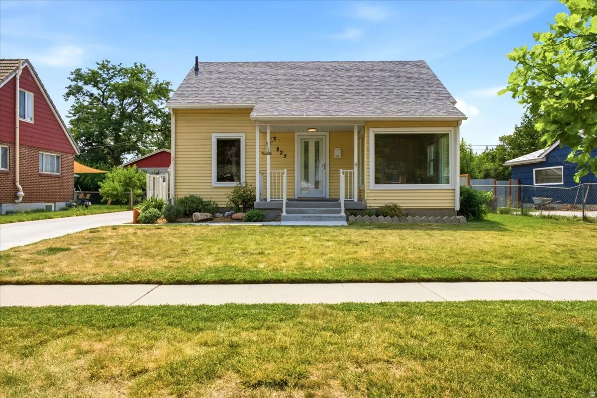 Yellow siding exterior with white trim, featuring a prominent picture window and a covered front porch with white railings