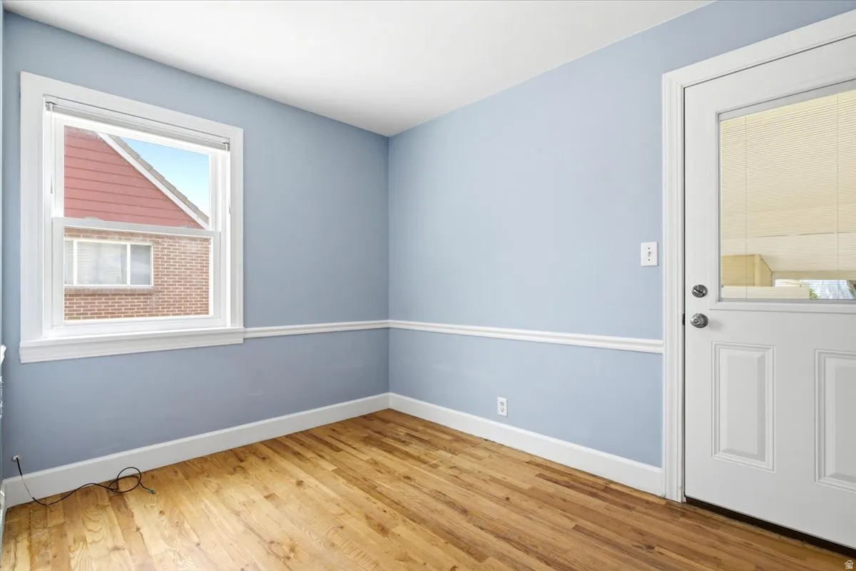Room featuring wood-finish flooring, light blue walls with white chair rail molding, and a white trim window
