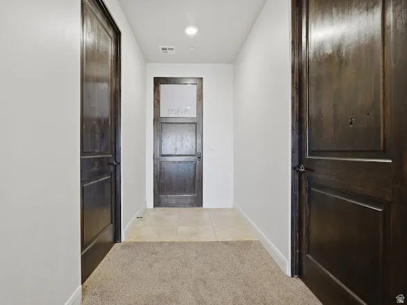 Hallway featuring dark wood-finish doors, recessed lighting, and mixed flooring with carpeting and tile