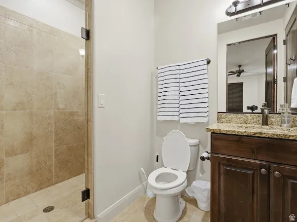 Tiled shower enclosure with a glass door, a dark wood-finish vanity with a stone countertop, and an integrated sink with a bronze-finish faucet