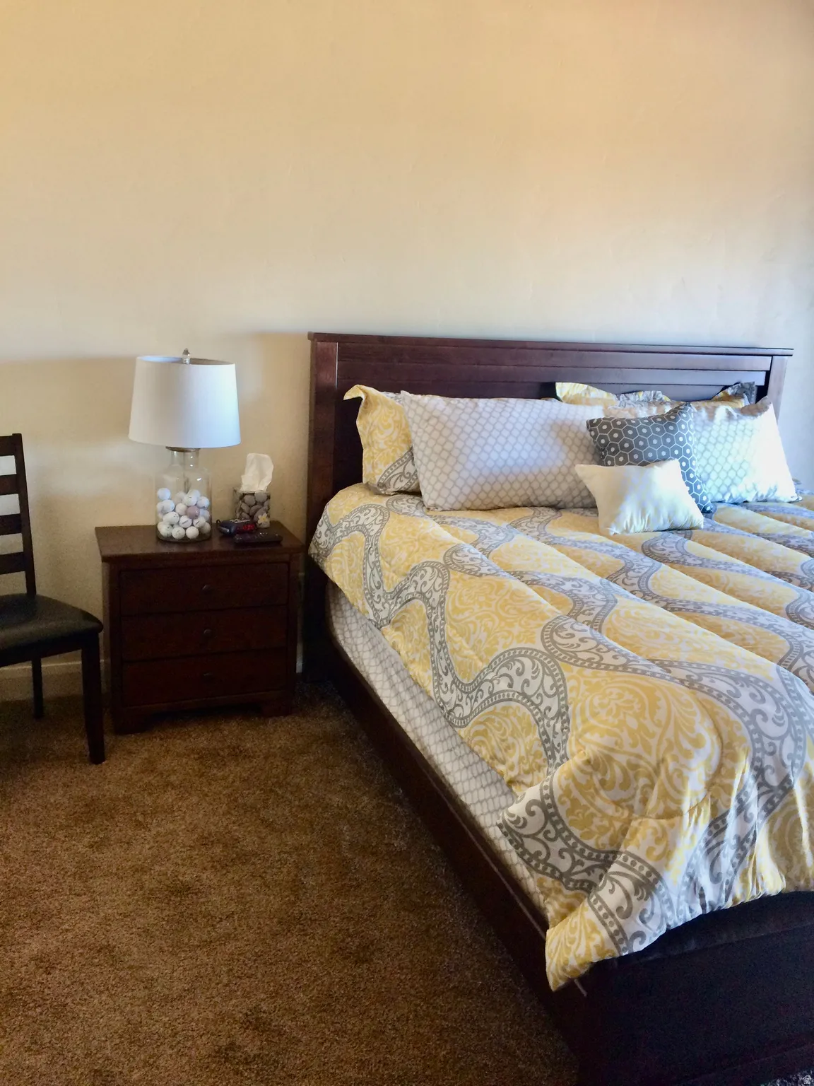 Bedroom featuring a dark wood bed frame with a matching three-drawer nightstand and brown carpeting