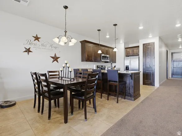Open-concept dining area featuring tile flooring, a dark wood dining table, and an overhead chandelier