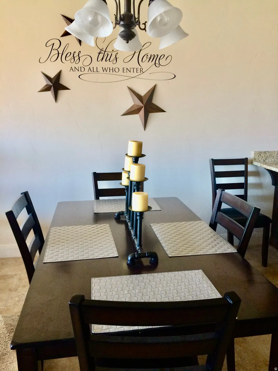 Dining area featuring a dark wood-finish table with coordinating chairs, an overhead chandelier with bell-shaped shades, and light-toned wall finishes
