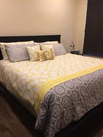 Bedroom with light-toned walls, dark window blinds, and dark-toned headboard