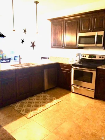 Kitchen with dark wood cabinetry, light-toned countertops, and stainless steel appliances