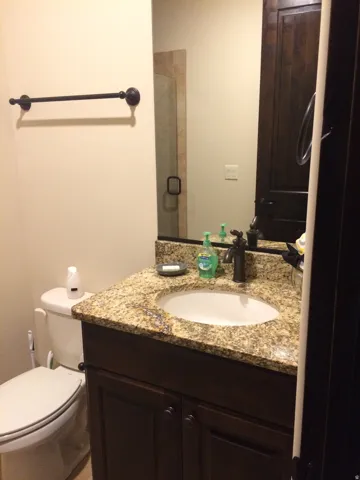 Vanity with granite countertop, integrated sink, and dark wood-finish cabinetry