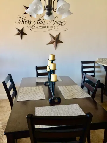 Dining area featuring a dark wood-finish table with coordinating chairs, an overhead chandelier with bell-shaped shades, and light-toned wall finishes