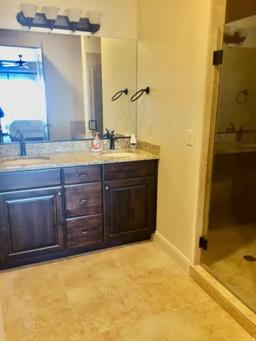 Dual sink vanity featuring dark wood cabinetry and a speckled countertop