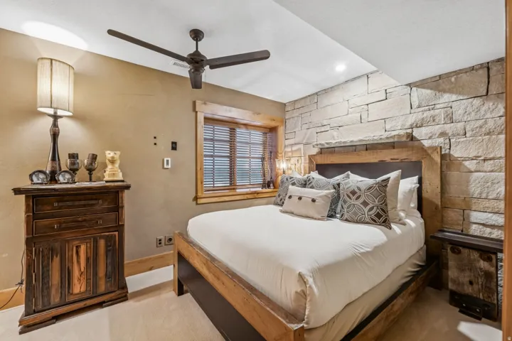 Bedroom featuring a natural stone accent wall, wood-finish window trim, a ceiling fan, recessed lighting, and carpet flooring