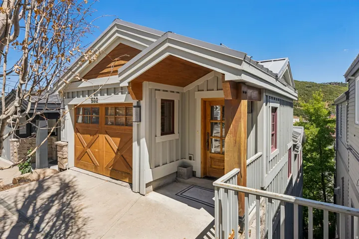 Contemporary exterior with board and batten siding, a natural wood garage door, and a natural wood entry door