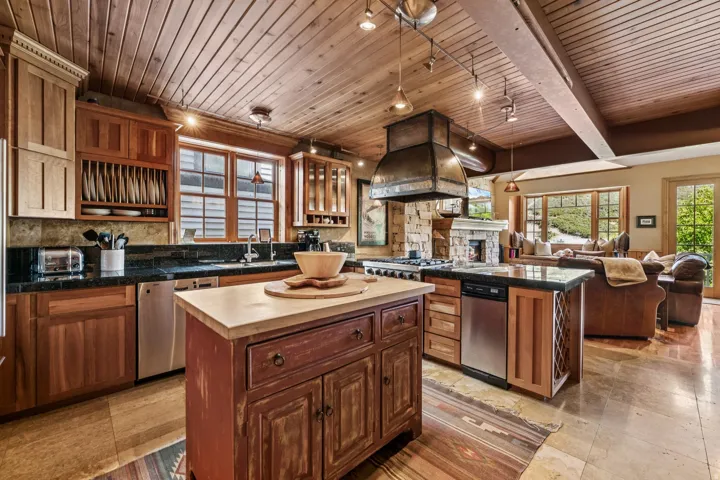 Kitchen featuring wood-paneled ceiling, wood cabinetry, stone backsplash, dark countertops, and stainless steel appliances