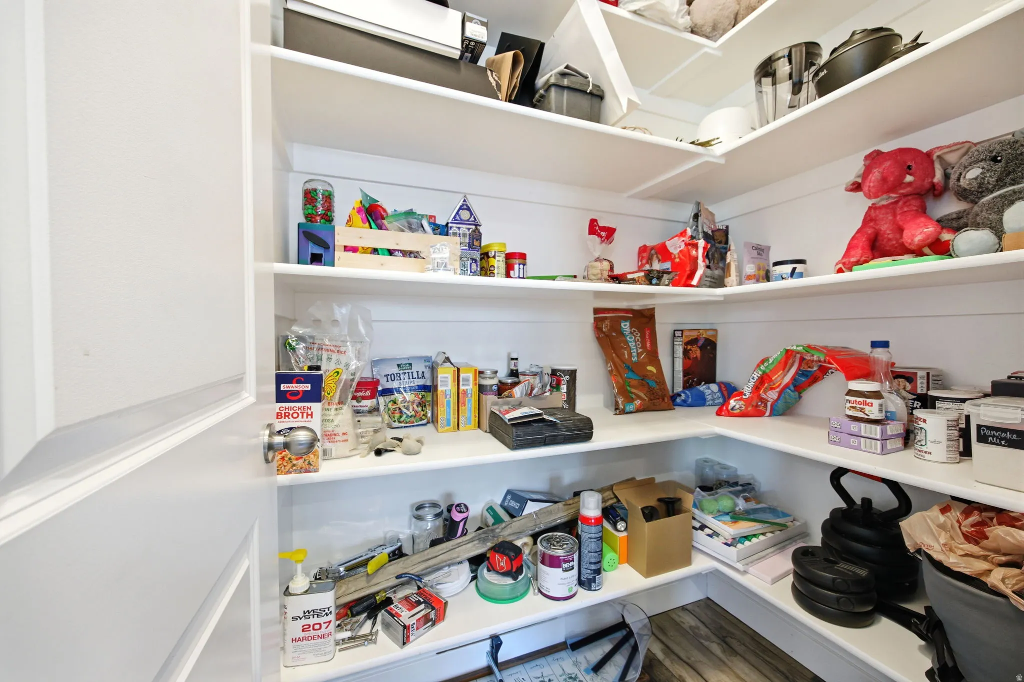 Corner pantry with white shelving and wood-finish flooring