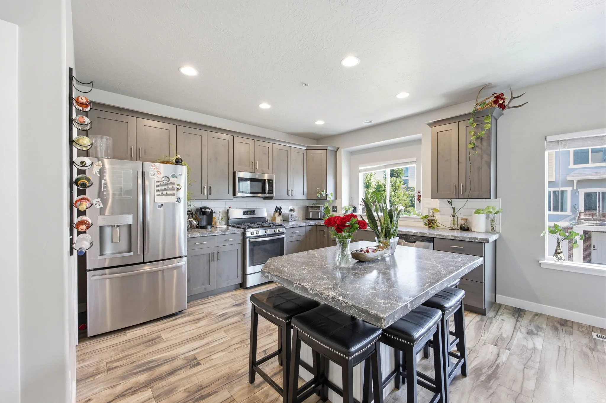 Kitchen featuring grey cabinetry, stainless steel appliances, a center island with a stone countertop, and wood-finish flooring