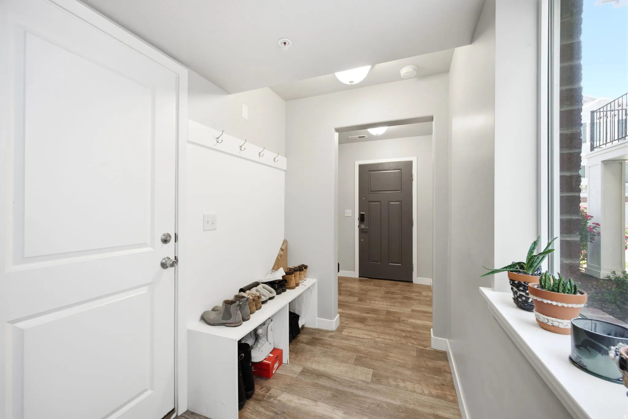 Entryway with wood-finish flooring, a white paneled door, built-in coat hooks, and a large window