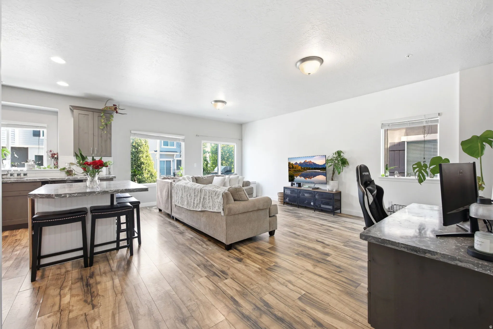 Open-concept living area featuring wood-finish flooring, white walls