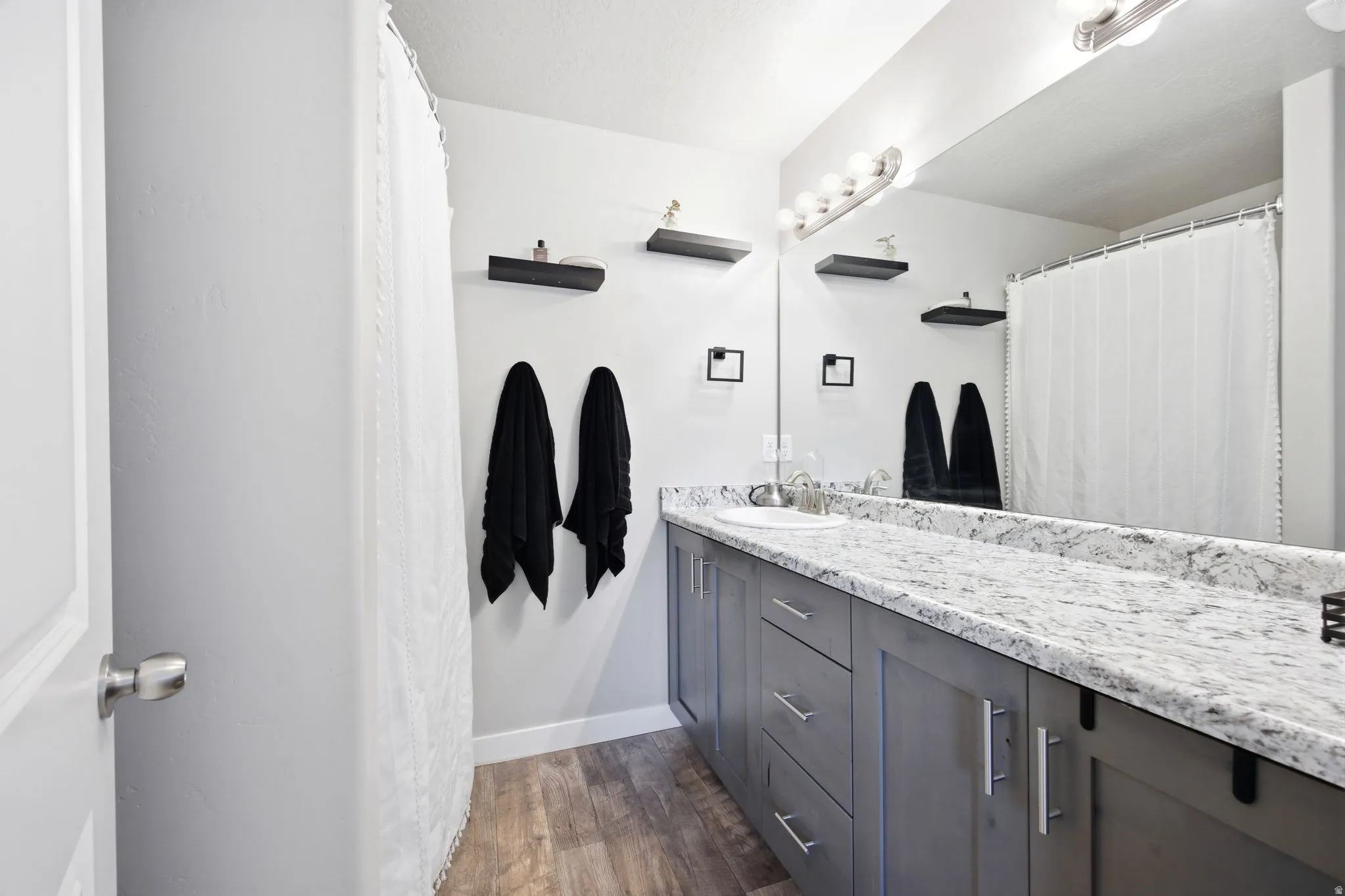 Primary Bathroom featuring a single vanity with gray cabinetry, a white countertop, and a built-in sink