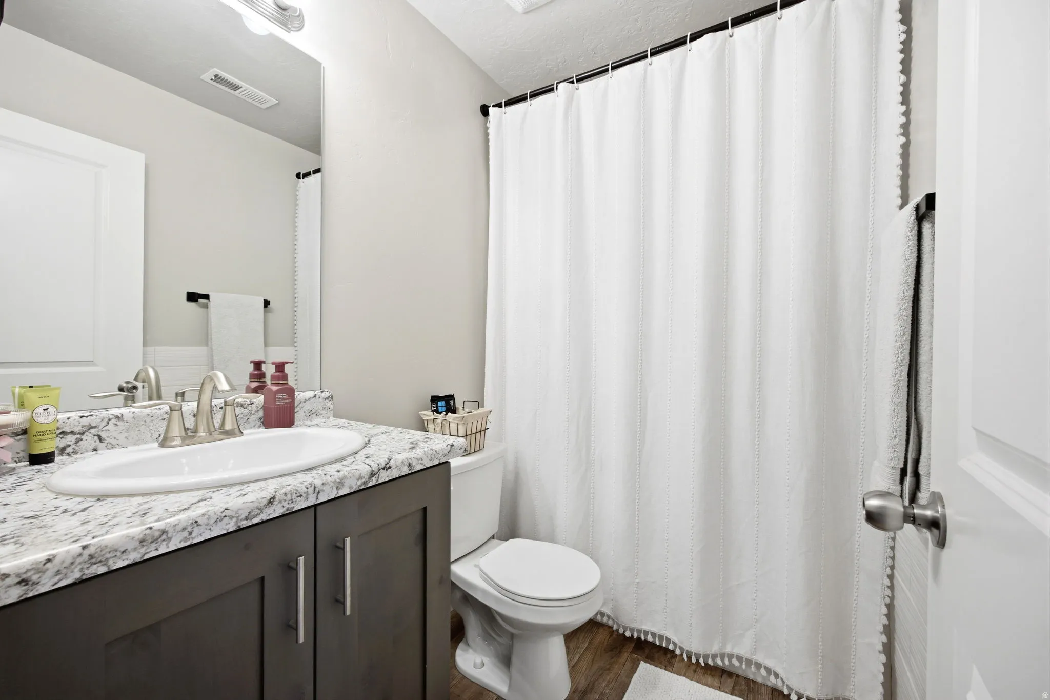 Bathroom featuring a dark wood vanity with brushed nickel hardware, a white oval sink