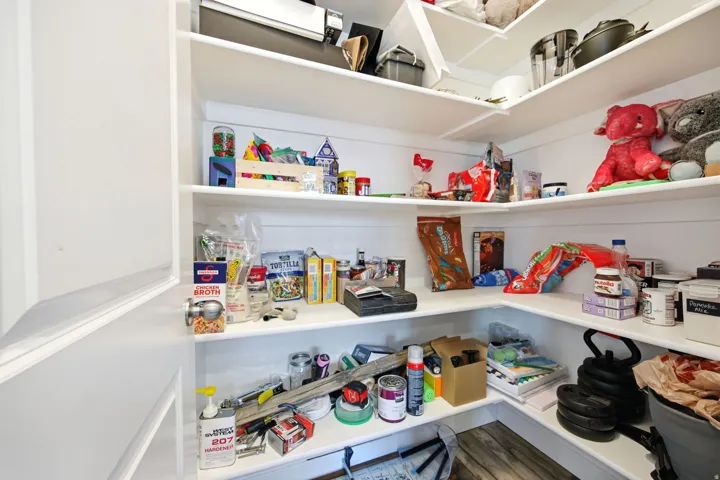 Corner pantry with white shelving and wood-finish flooring