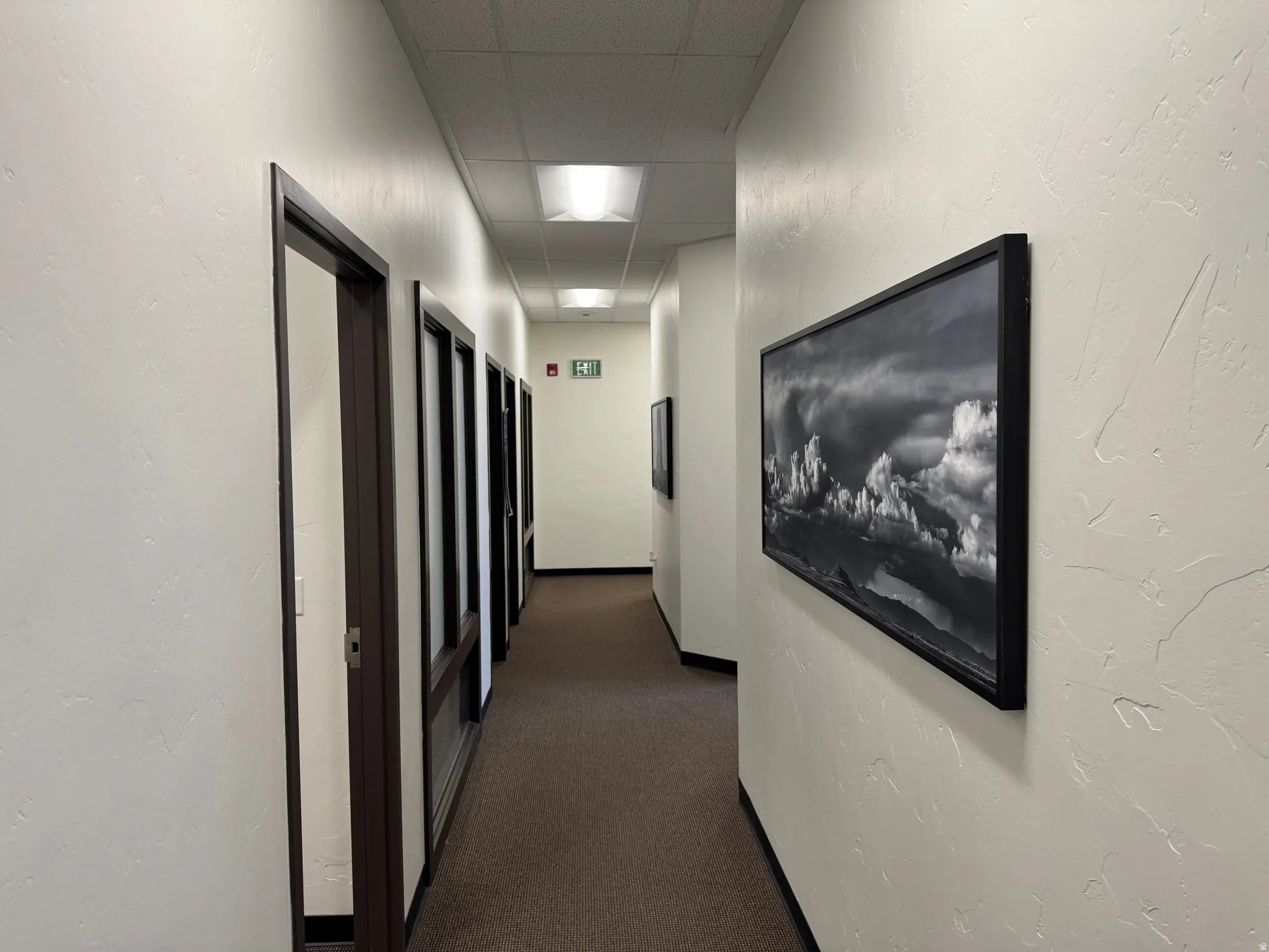 Corridor featuring textured walls, recessed ceiling lighting, and dark framed doorways