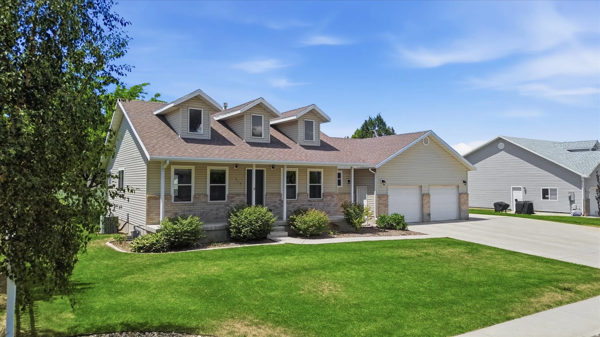 Ranch-style exterior with stone and siding facade, dormer windows, and an attached two-car garage