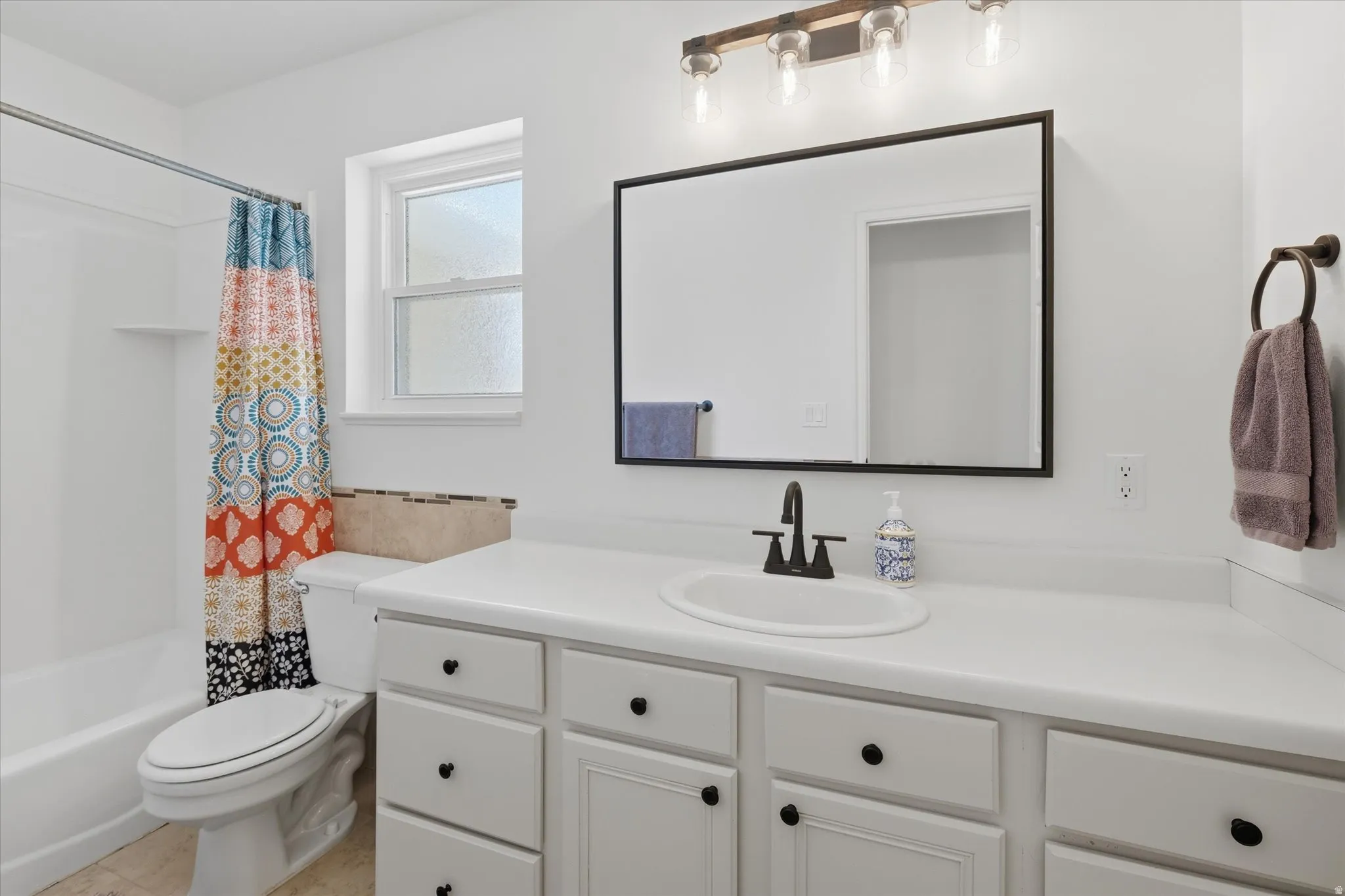 White vanity with ample counter space, integrated sink, and matte black faucet