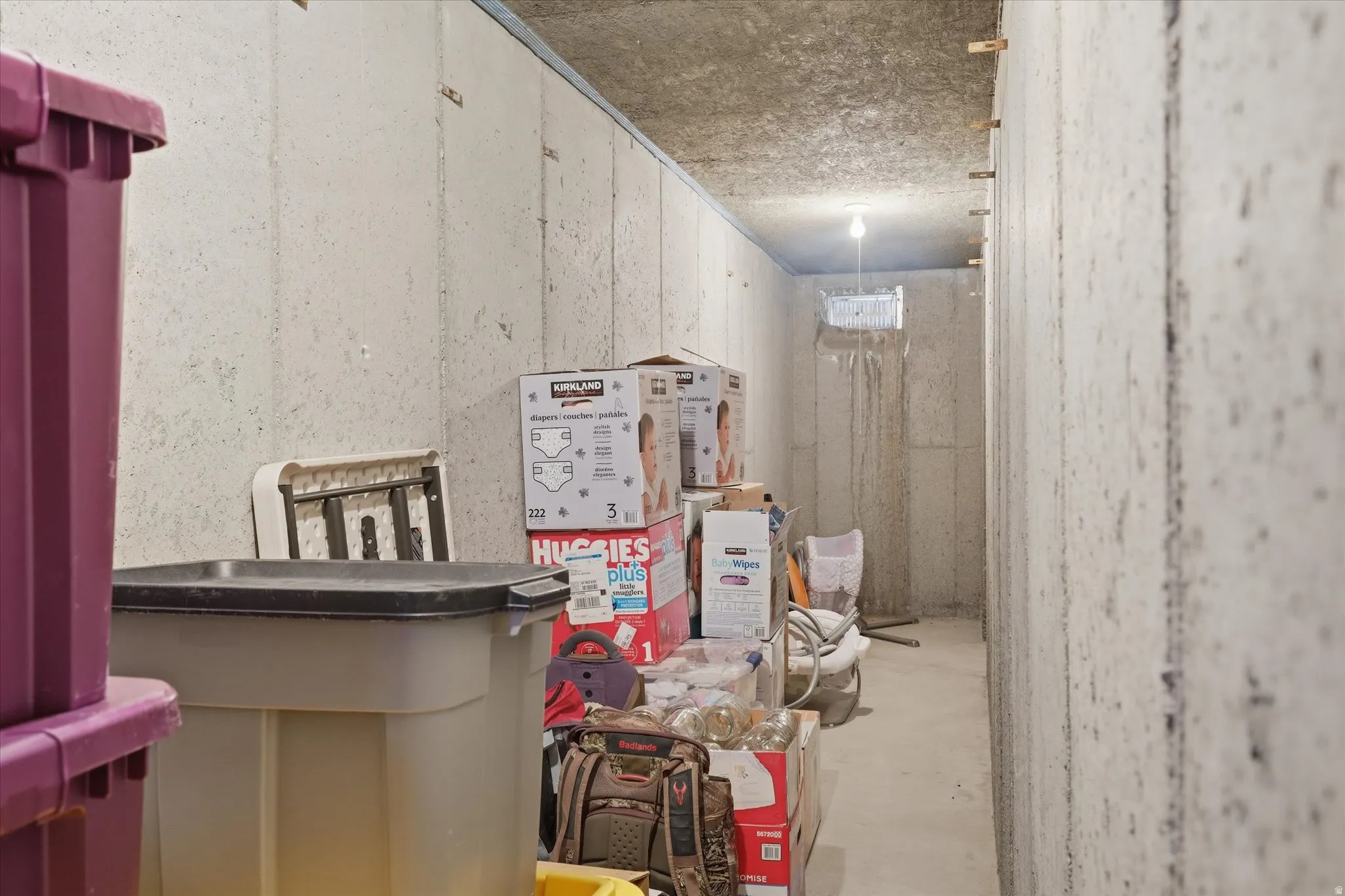 Unfinished concrete basement with overhead lighting and visible concrete block walls