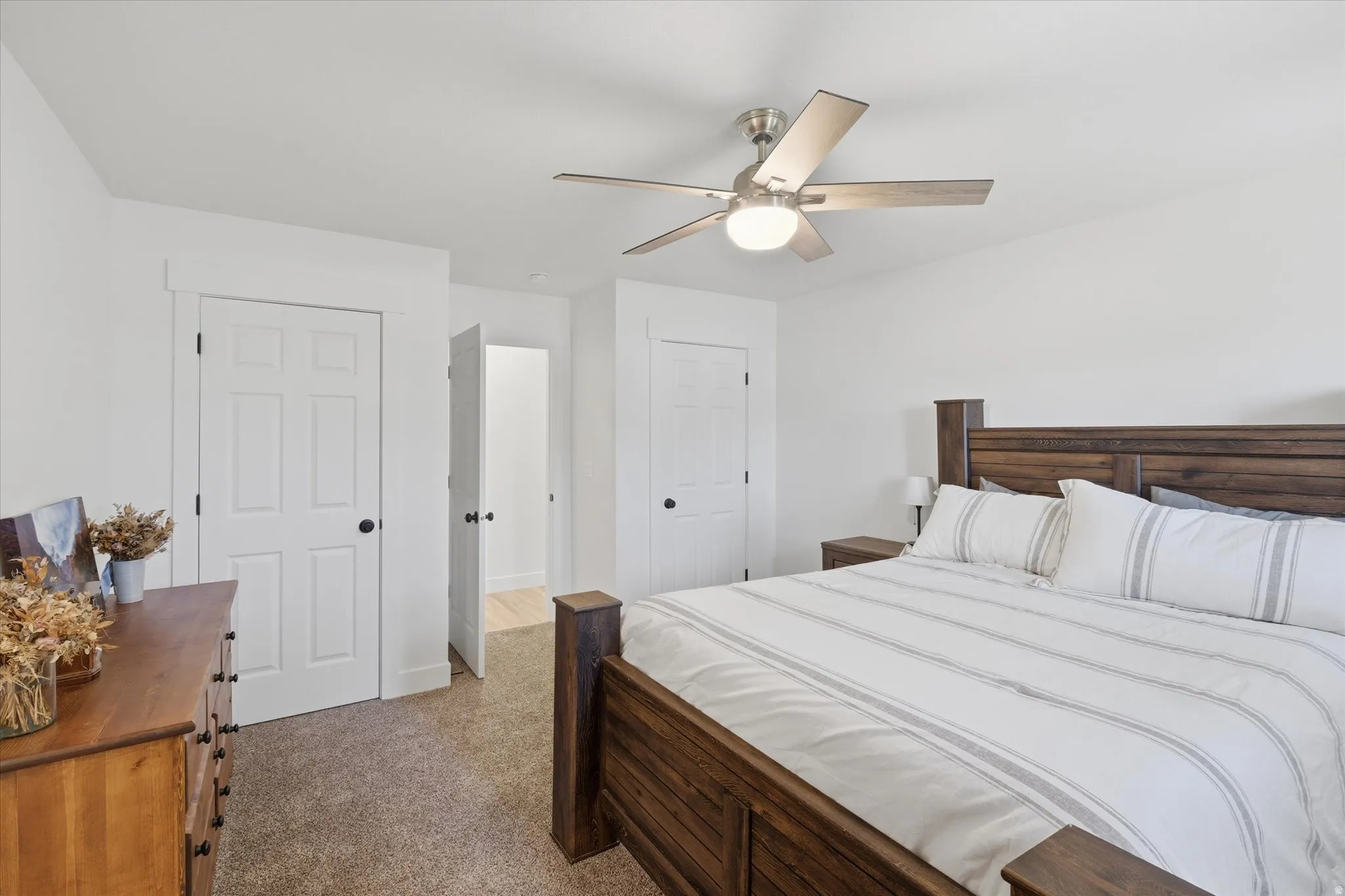 Spacious bedroom featuring neutral carpeting, white walls, and a contemporary ceiling fan
