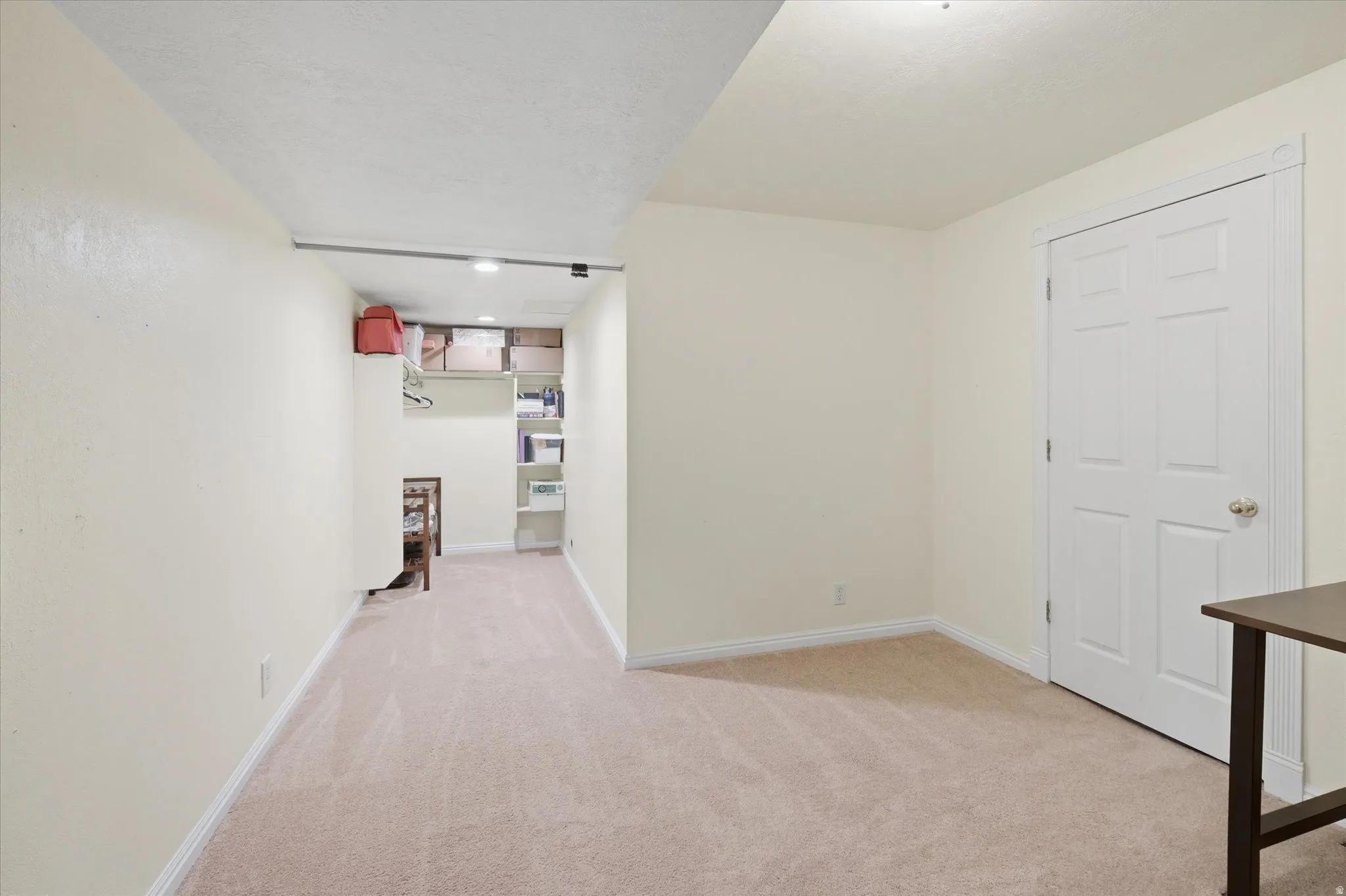 Carpeted room featuring a white paneled door with a brass-finish knob