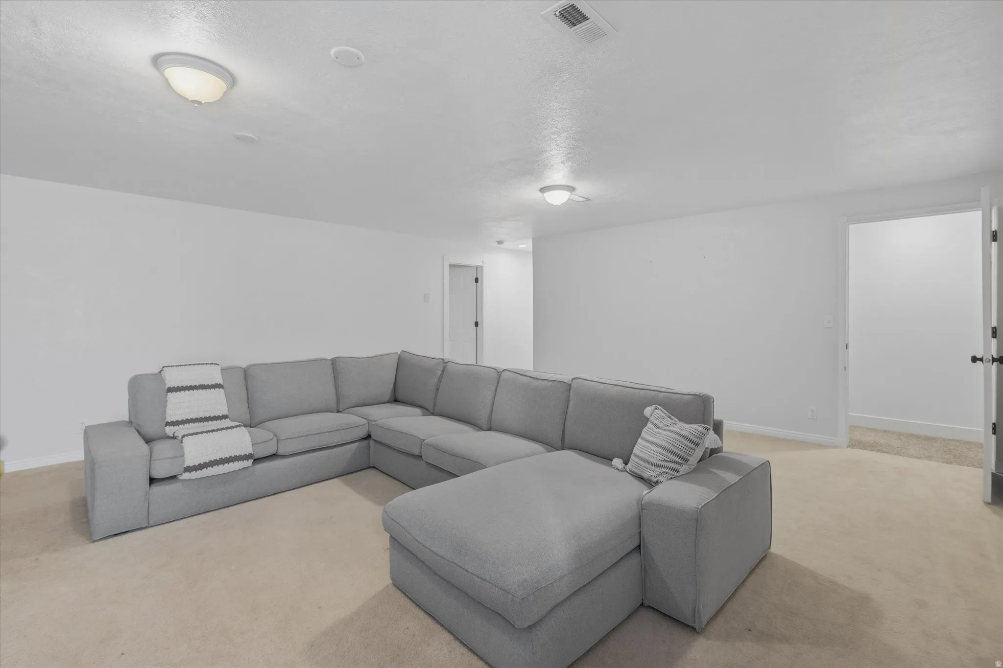 Carpeted room with white walls, two flush-mount ceiling lights, and an open doorway