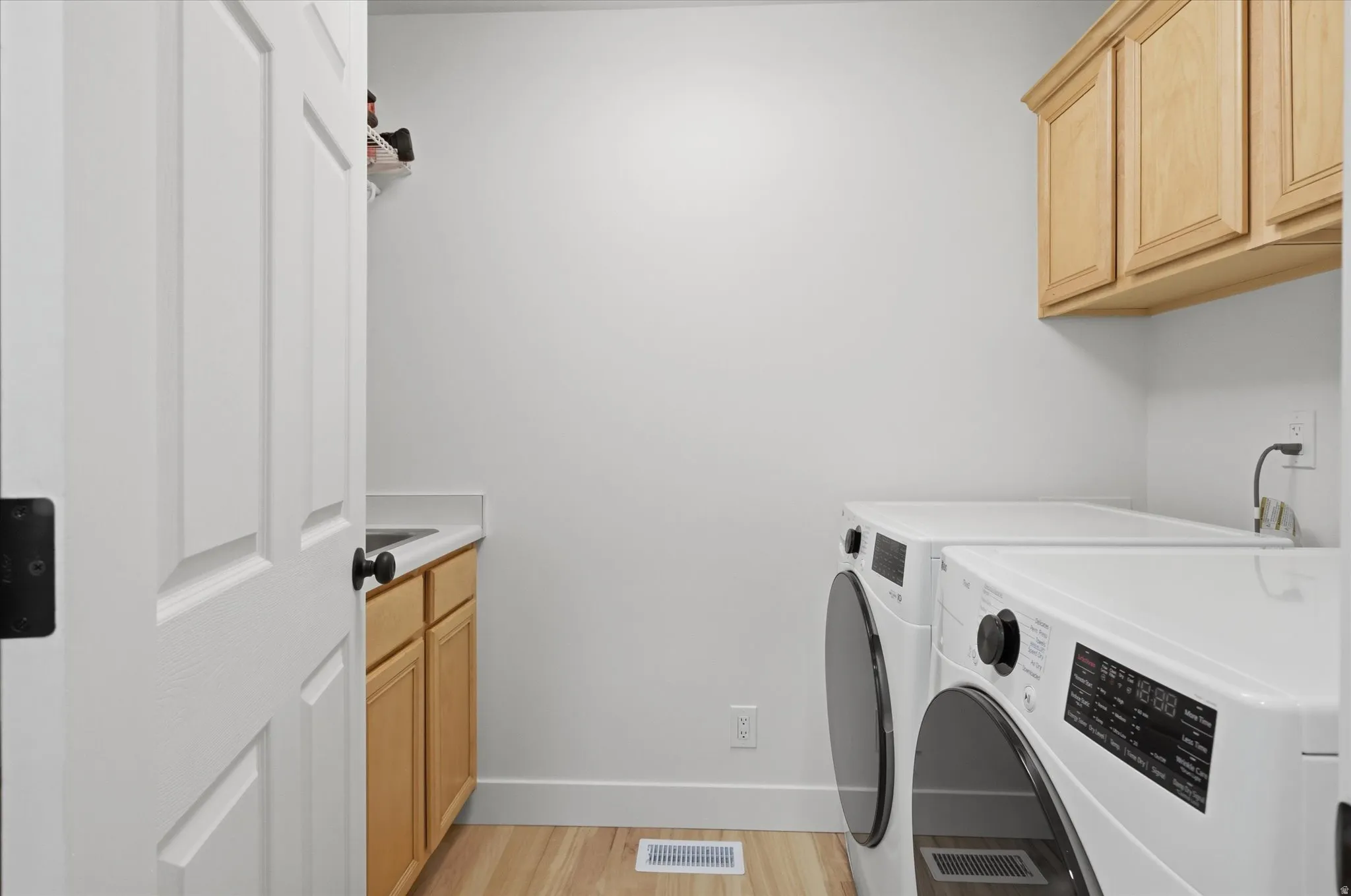 Dedicated laundry area featuring wood-finish flooring and light-toned walls