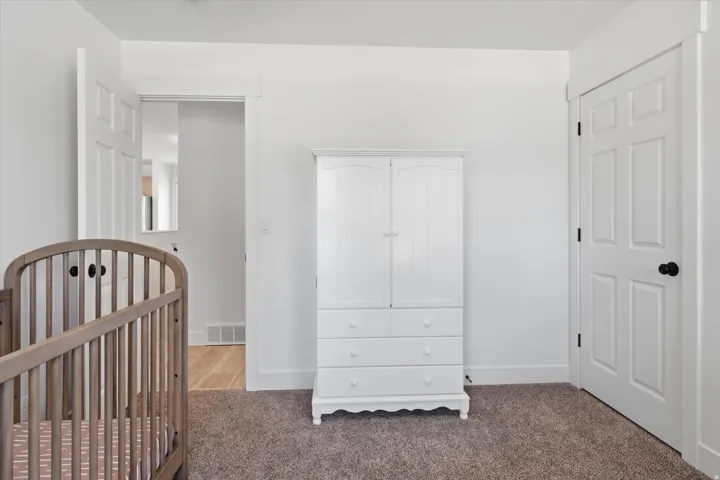 Plush carpet flooring, white painted walls, and white trim molding create a neutral interior space