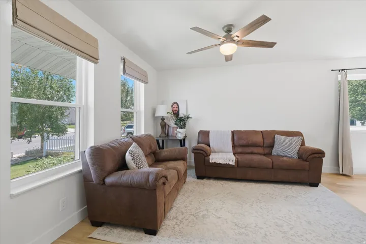 Living area featuring light wood-finish flooring, white walls, and multiple windows with blinds