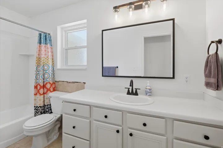 White vanity with ample counter space, integrated sink, and matte black faucet