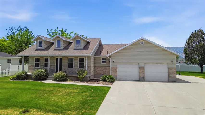 Cottage-style residence featuring a two-car garage, dormer windows, and a covered front porch