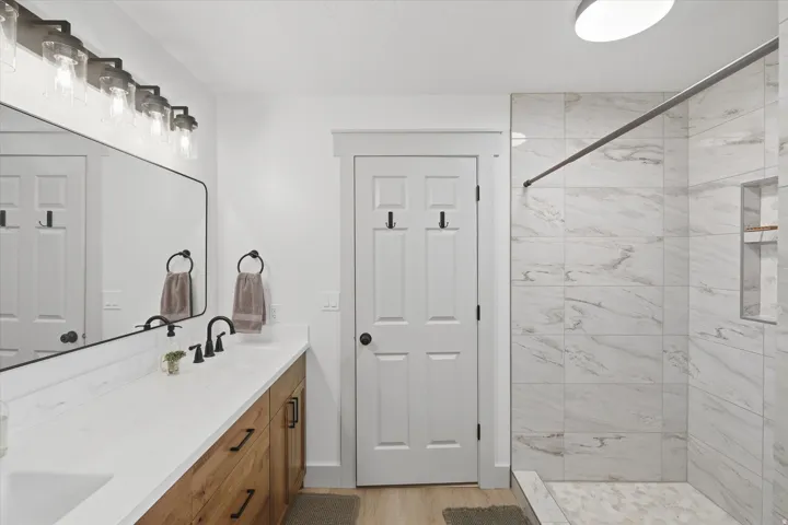 Bathroom featuring a wood-finish vanity with a white countertop, dual sinks, and matte black fixtures