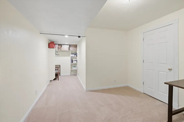 Carpeted room featuring a white paneled door with a brass-finish knob
