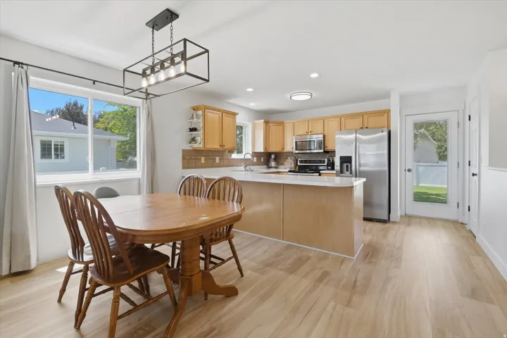Open-concept kitchen and dining area featuring light wood-finish flooring, a kitchen island with a white countertop, and light natural wood cabinetry