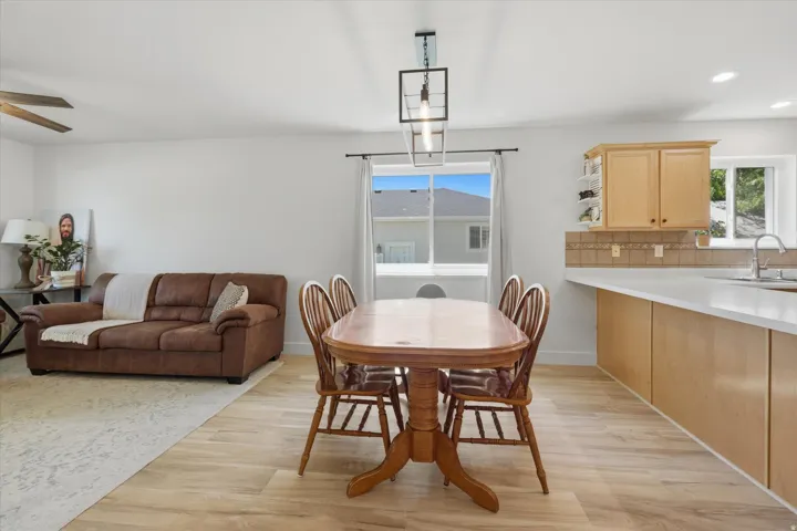 Open-concept dining area featuring wood-finish flooring, a contemporary pendant light fixture, and a large window