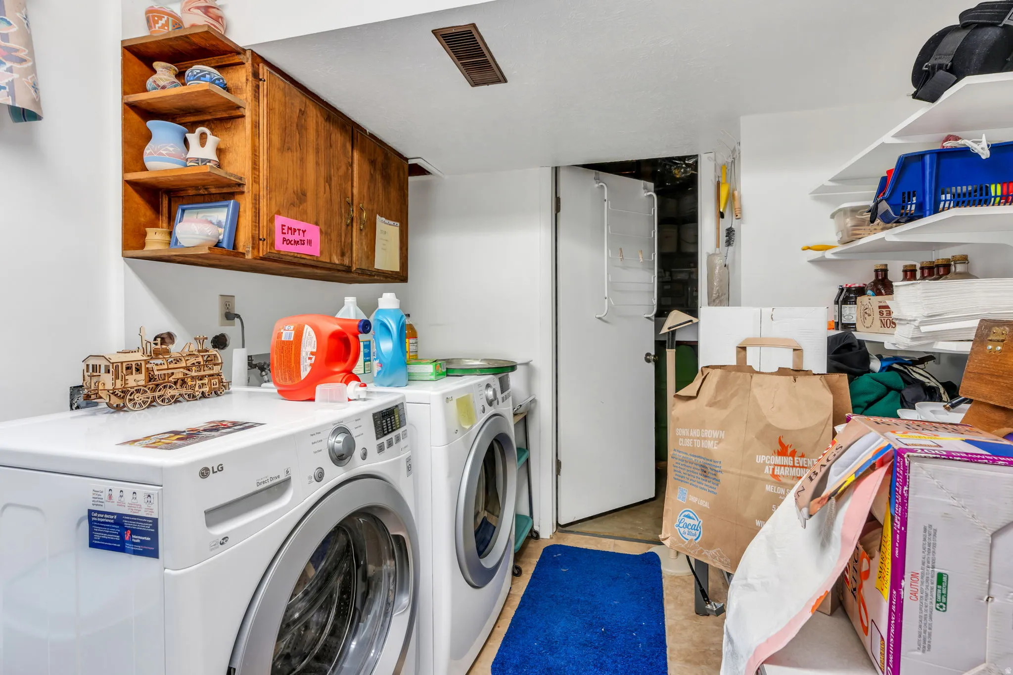 Dedicated utility room featuring upper wood cabinetry, open shelving, and built-in wall shelving