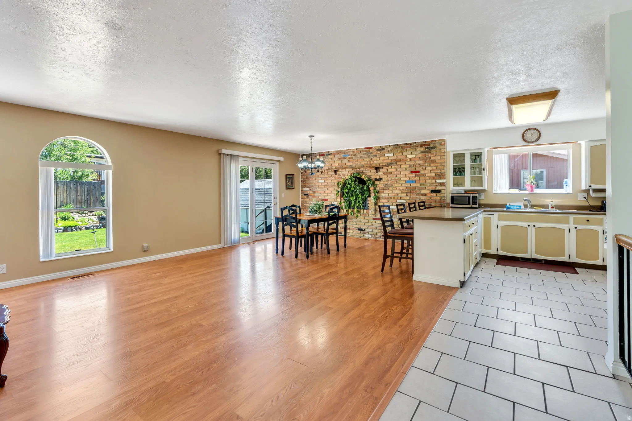 Open-concept living area featuring wood-finish flooring and an arched window