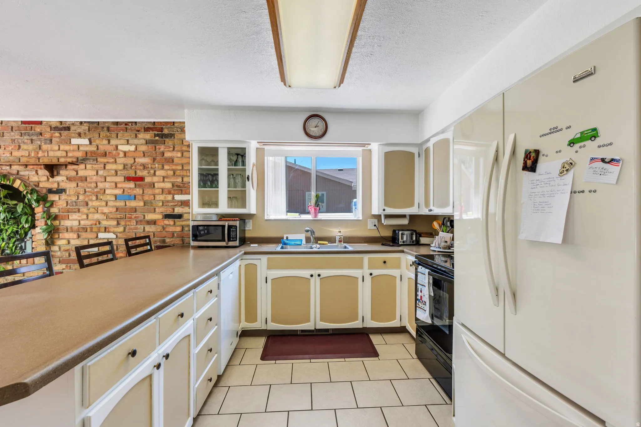 Kitchen featuring white cabinetry with light-toned inserts, a brown countertop, and tile flooring