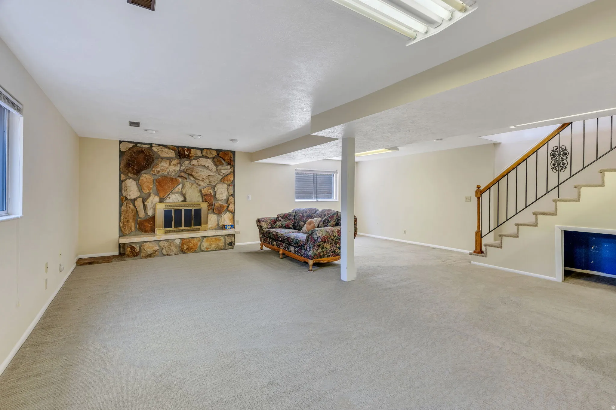 Spacious interior with stone-faced fireplace, light-toned carpeting, and neutral wall paint