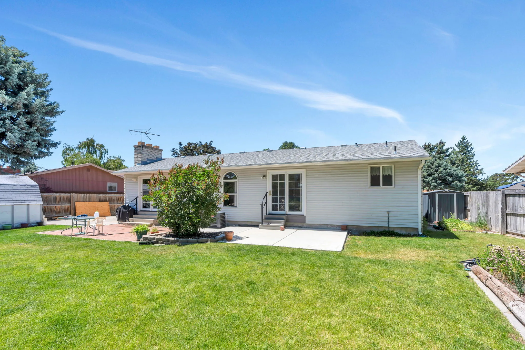 Expansive rear yard featuring a wide concrete patio, a paver patio area, and a large grassy lawn