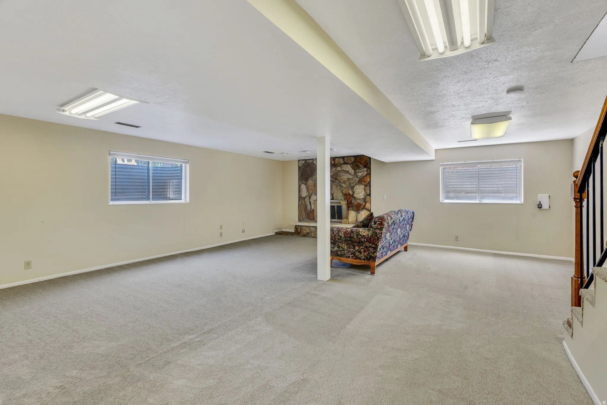 Spacious finished lower level featuring light-toned carpeting, a built-in stone fireplace, two egress windows, and recessed lighting