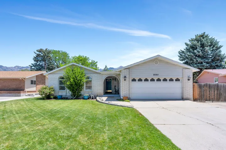 Ranch-style exterior featuring a light brick facade, white siding, an attached two-car garage, and a concrete driveway