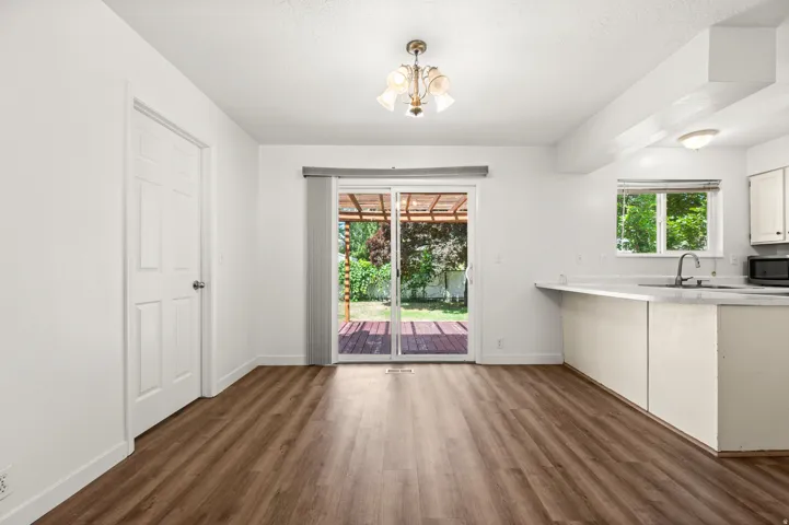 Interior space featuring wood-finish flooring, white walls, and a multi-pane glass sliding door