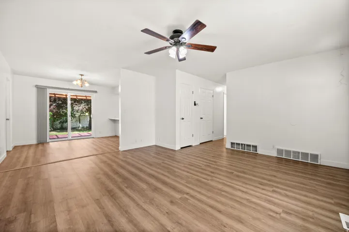 Spacious interior featuring wood-finish flooring, white walls, and a ceiling fan with integrated lighting